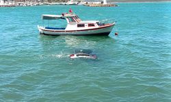 Denize uçan otomobilinin üzerinde oturup yardım bekledi